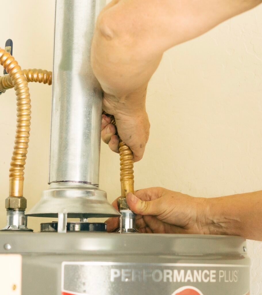 Technician connecting flexible copper water lines to a residential water heater