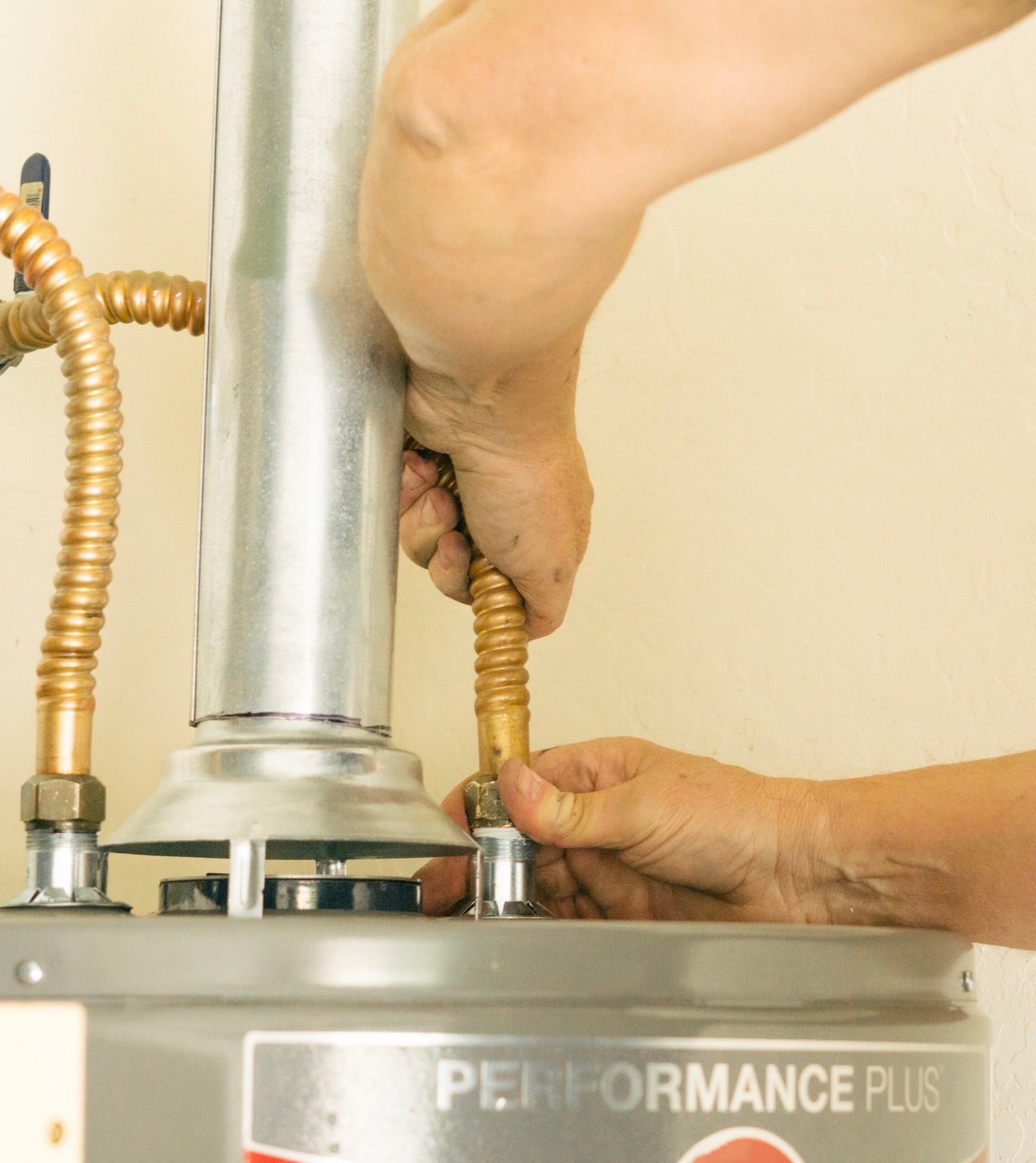 Technician connecting flexible copper water lines to a residential water heater