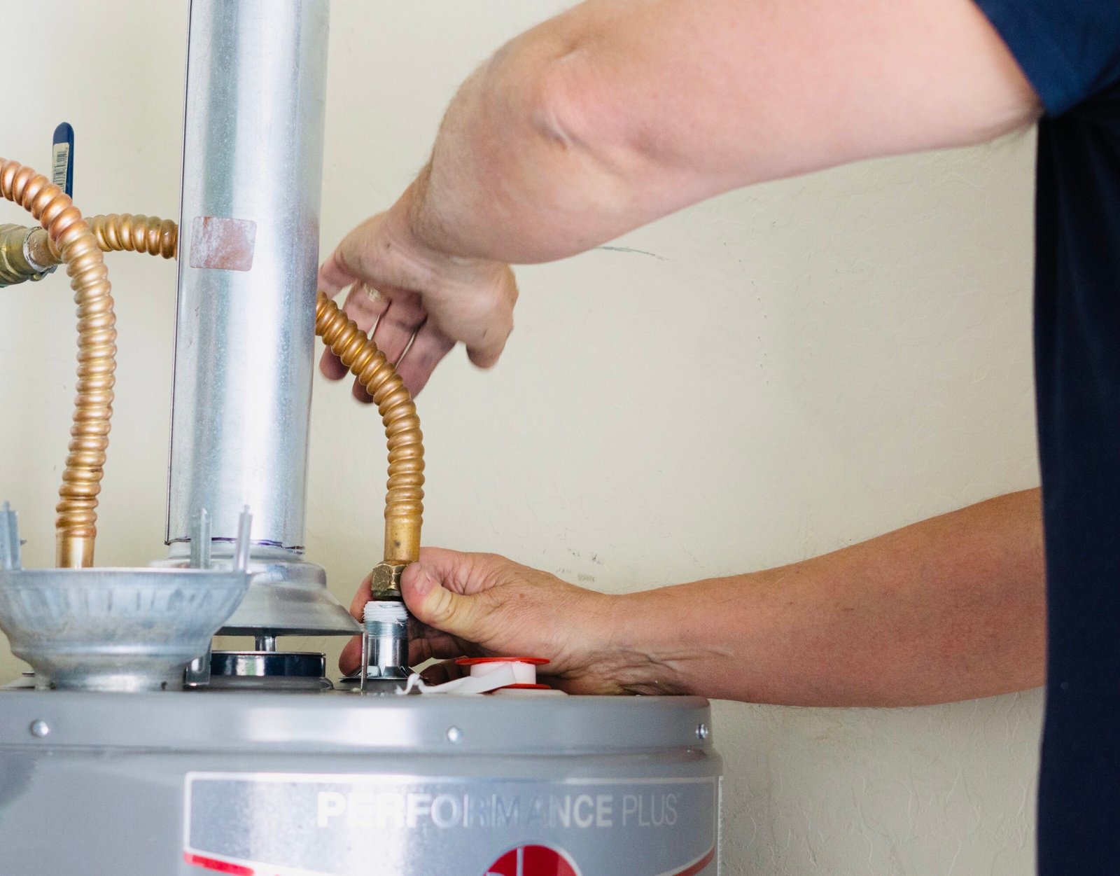 Plumber connecting a gas line to a residential water heater during service